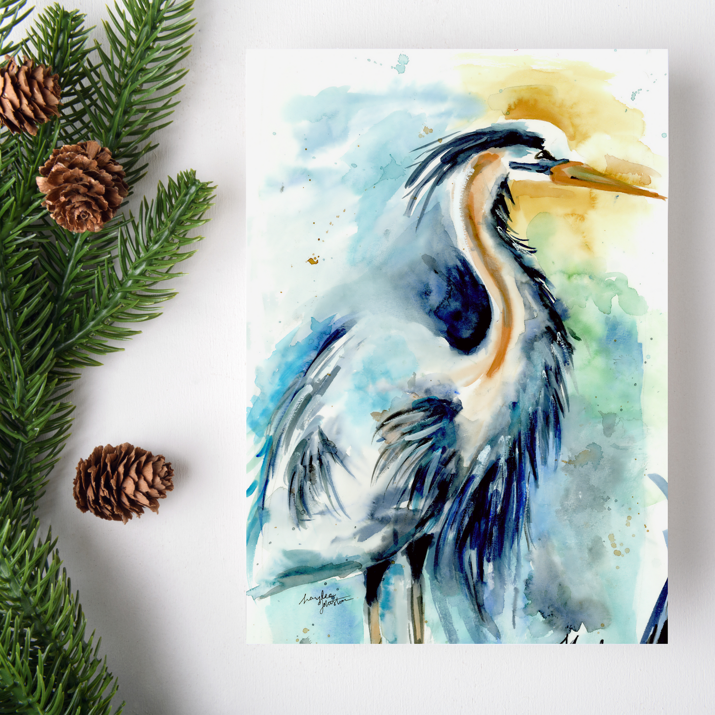 Flat cardstock note card featuring original watercolor piece Male Heron on a white background. Green pine fronds with brown pinecones decorate the left side.