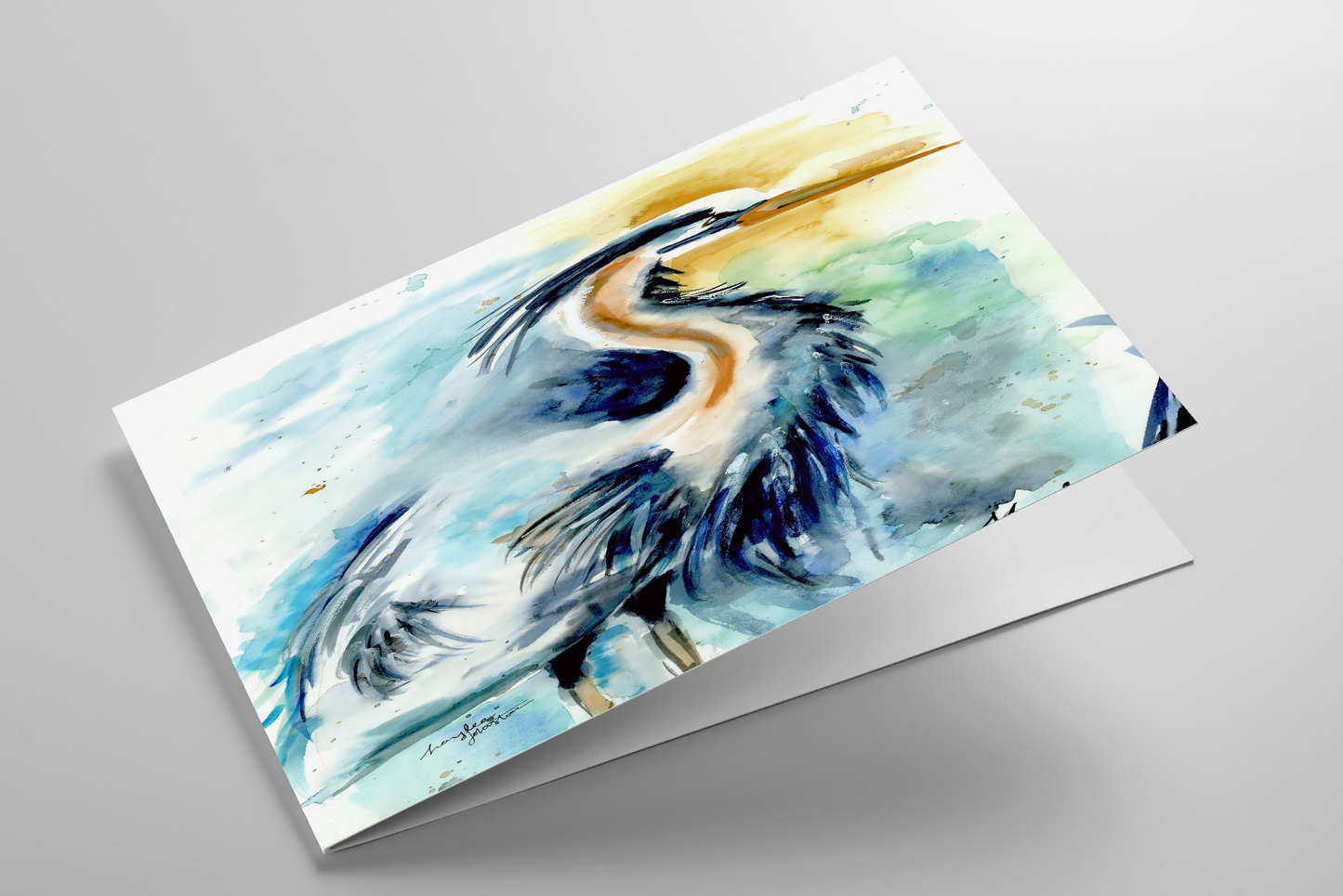 Folding greeting card featuring original watercolor piece Male Heron laying down showing cardstock thickness and blank inside.