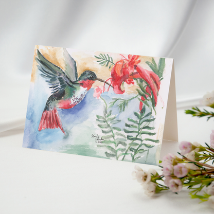 Folding cardstock greeting card featuring original watercolor piece A Garden Visit resting open on a white tablecloth with pink flowers in the foreground.