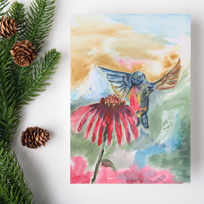 Flat cardstock note card featuring original watercolor piece A Jeweled Messenger on a white background. Green pine fronds with brown pinecones decorate the left side.