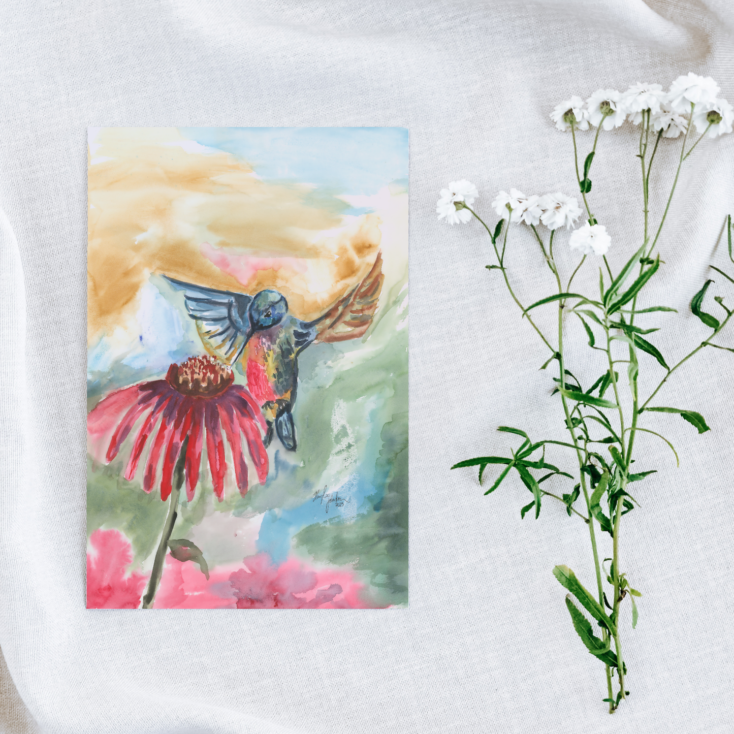 Flat cardstock note card featuring original watercolor piece A Jeweled Messenger on a white linen background next to fresh white flowers.