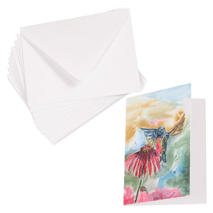 Folding cardstock greeting card featuring original watercolor piece A Jeweled Messenger laying next to a stack of euro flap envelopes.