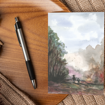 Flat cardstock note card featuring original watercolor piece A Walk in the Forest displayed on a wooden surface beside a black and silver pen.