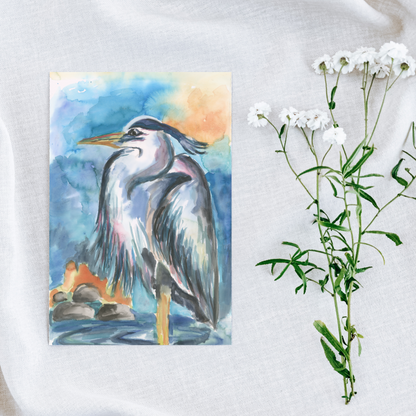 Flat cardstock note card featuring original watercolor piece Dark Heron on a white linen background next to fresh white flowers.