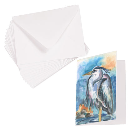 Folding cardstock greeting card featuring original watercolor piece Dark Heron laying next to a stack of euro flap envelopes.