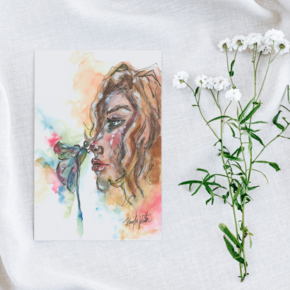 Flat cardstock note card featuring original watercolor piece Dragonfly Girl on a white linen background next to fresh white flowers.