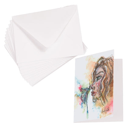 Folding cardstock greeting card featuring original watercolor piece Dragonfly Girl laying next to a stack of euro flap envelopes.