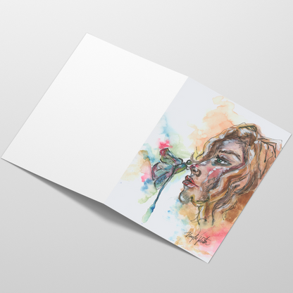 Folding cardstock greeting card featuring original watercolor piece Dragonfly Girl laying open in a table with the outside facing up.