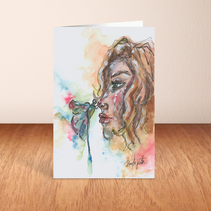 Folding cardstock greeting card featuring original watercolor piece Dragonfly Girl standing upright on a wooden table.