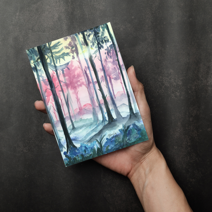 Flat cardstock note card featuring original watercolor piece Fairy Forest in a person's right hand. The background transitions from black at the bottom to a dull gray at the top.