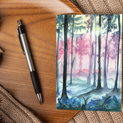 Flat cardstock note card featuring original watercolor piece Fairy Forest displayed on a wooden surface beside a black and silver pen.