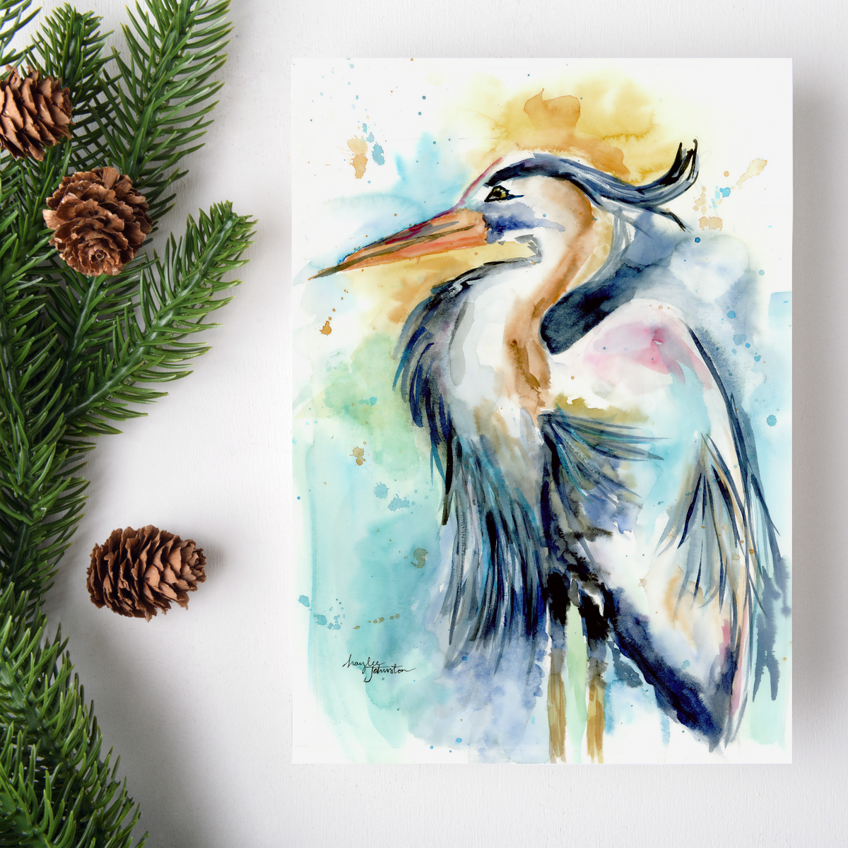 Flat cardstock note card featuring original watercolor piece Female Heron on a white background. Green pine fronds with brown pinecones decorate the left side.