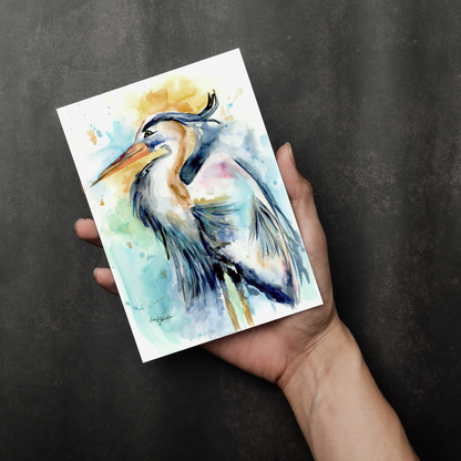 Flat cardstock note card featuring original watercolor piece Female Heron in a person's right hand. The background transitions from black at the bottom to a dull gray at the top.