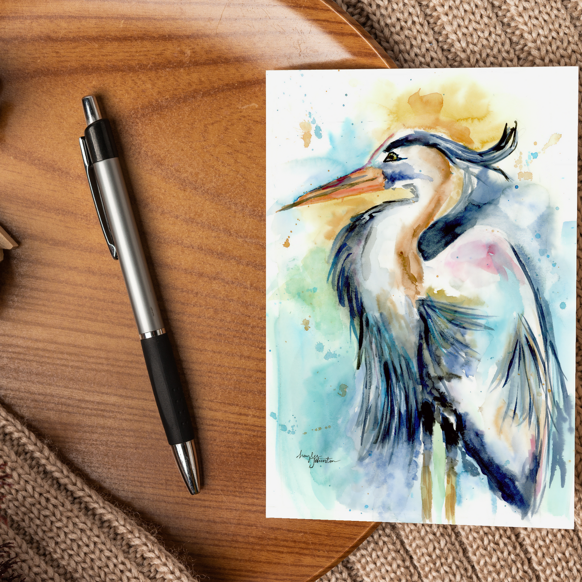 Flat cardstock note card featuring original watercolor piece Female Heron displayed on a wooden surface beside a black and silver pen.