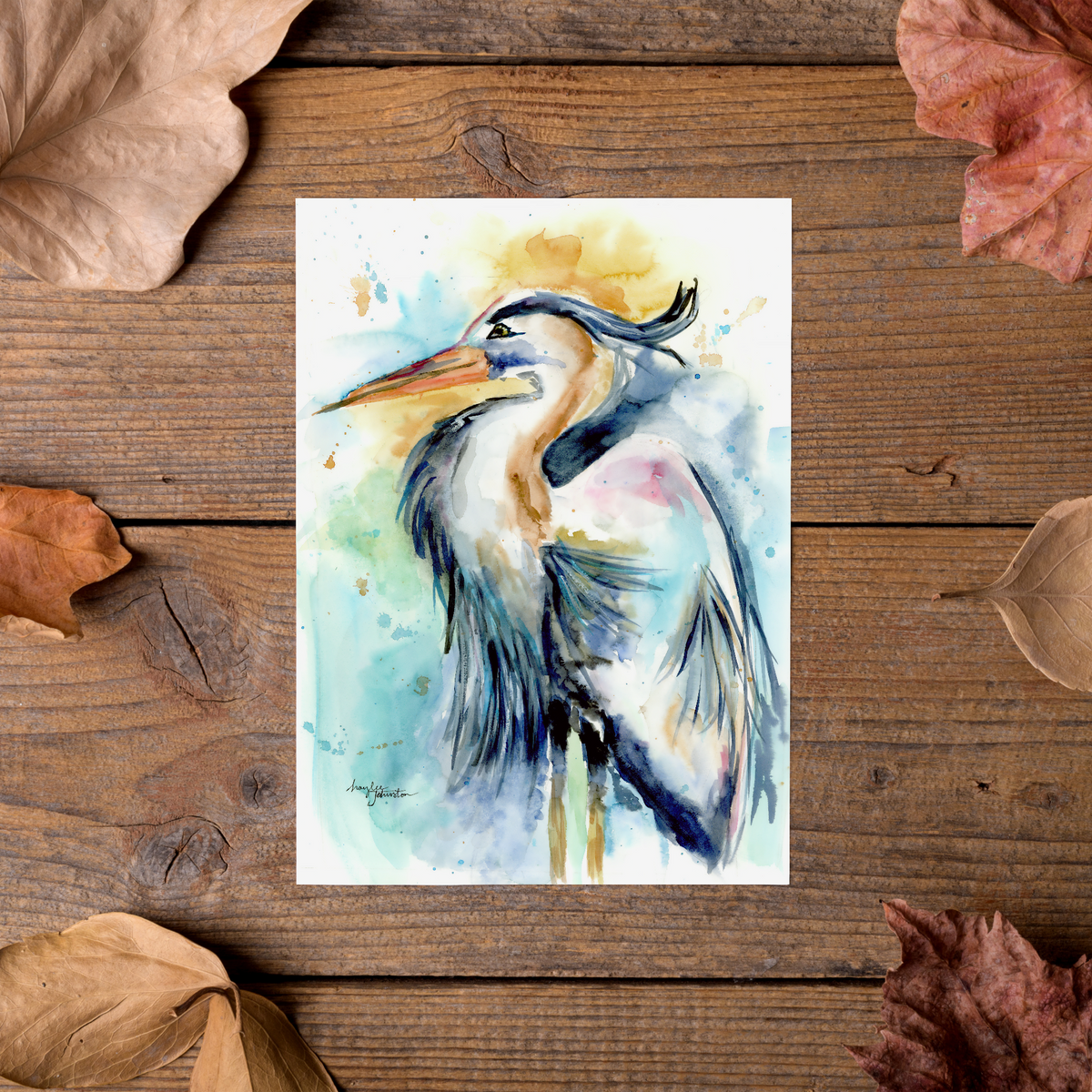 Flat cardstock note card featuring original watercolor piece Female Heron styled on rustic wooden boards with dried autumn leaves.