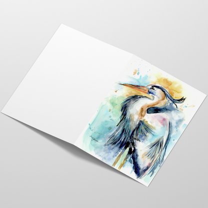 Folding cardstock greeting card featuring original watercolor piece Female Heron laying open in a table with the outside facing up.