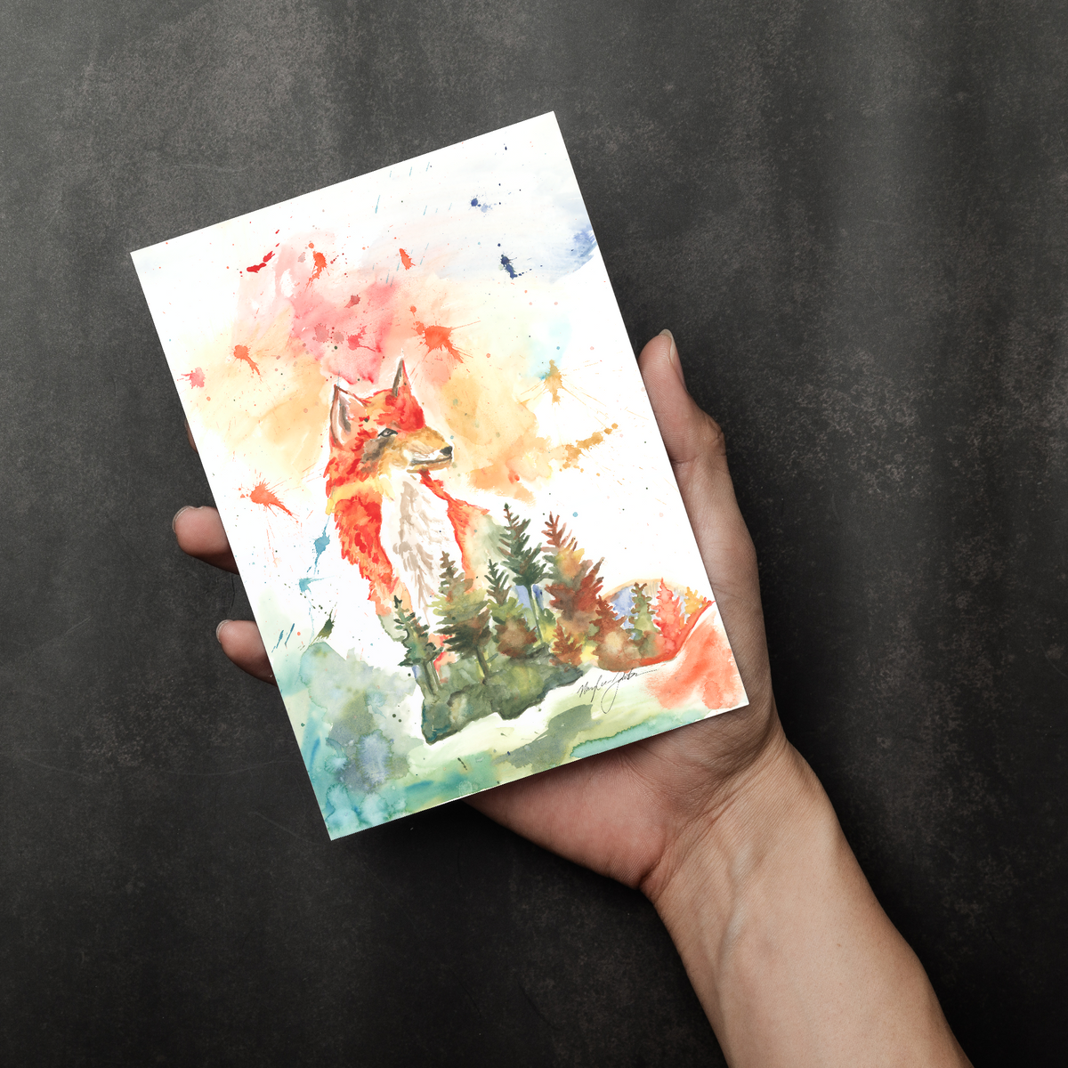 Flat cardstock note card featuring original watercolor piece Forest Fox in a person's right hand. The background transitions from black at the bottom to a dull gray at the top.