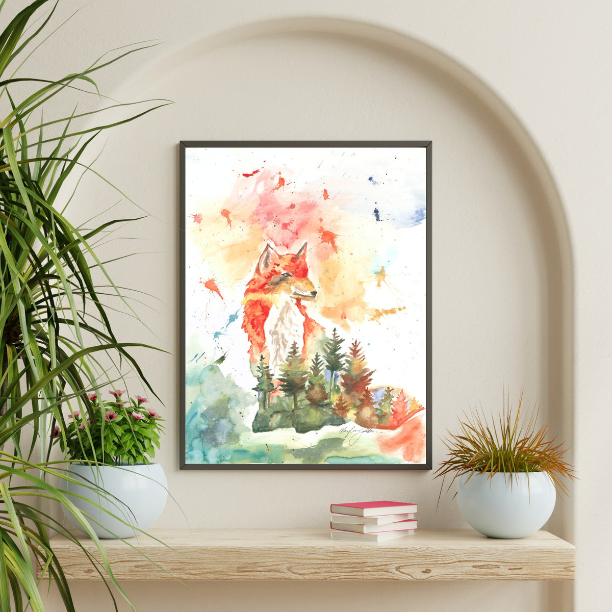 Giclée Forest Fox in a thin black frame hangs inside an arched alcove on a cream wall, above a chunky light wood shelf styled with a stack of pink books and two round white pots holding green and bronze plants.