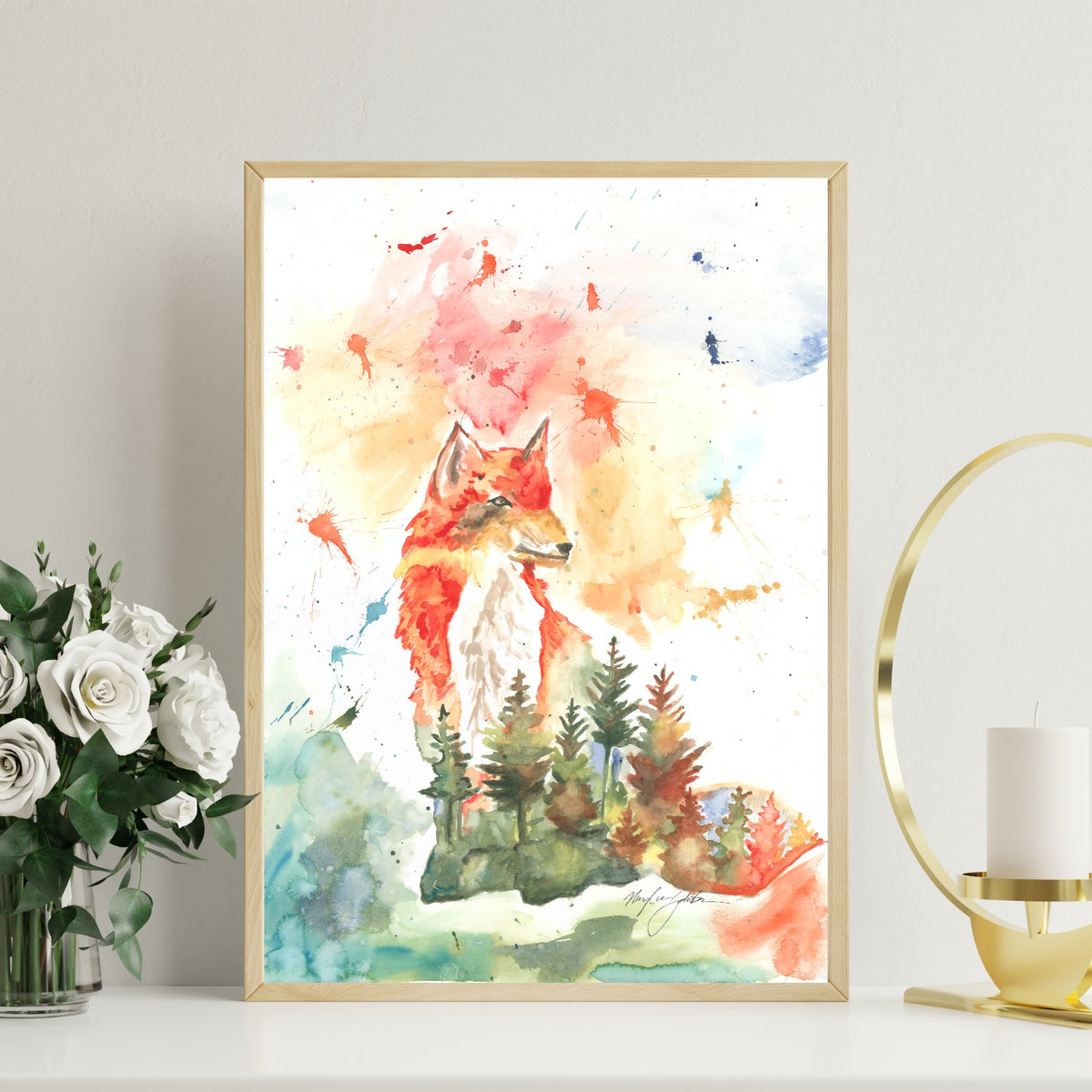 Giclée Forest Fox in a slim light wood frame stands on a white tabletop against a pale wall, with a glass vase of white roses to the left and a modern gold ring candle holder with a white pillar candle to the right.