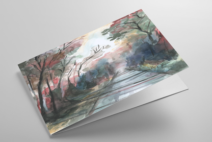 Folding greeting card featuring original watercolor piece Forest Road laying down showing cardstock thickness and blank inside.