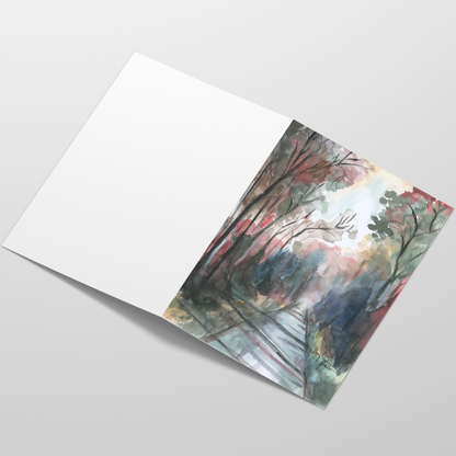 Folding cardstock greeting card featuring original watercolor piece Forest Road laying open in a table with the outside facing up.
