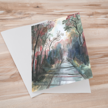 Folding cardstock greeting card featuring original watercolor piece Forest Road laying one on top of another.