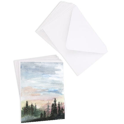 A stack of flat cardstock note cards featuring original watercolor piece Forest Skyline next to a stack of the matching euro flap envelopes.