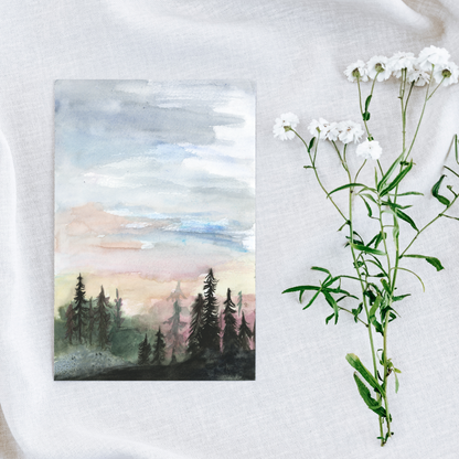 Flat cardstock note card featuring original watercolor piece Forest Skyline on a white linen background next to fresh white flowers.