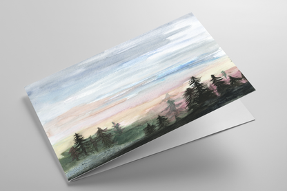 Folding greeting card featuring original watercolor piece Forest Skyline laying down showing cardstock thickness and blank inside.