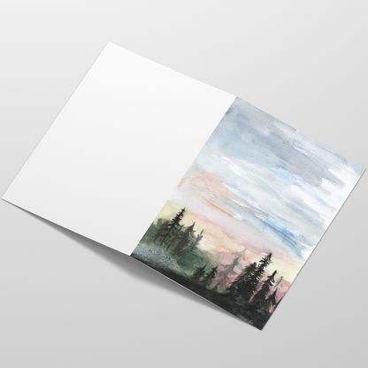 Folding cardstock greeting card featuring original watercolor piece Forest Skyline laying open in a table with the outside facing up.