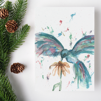 Flat cardstock note card featuring original watercolor piece Hovering Hummingbird on a white background. Green pine fronds with brown pinecones decorate the left side.