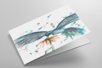 Folding greeting card featuring original watercolor piece Hovering Hummingbird laying down showing cardstock thickness and blank inside.