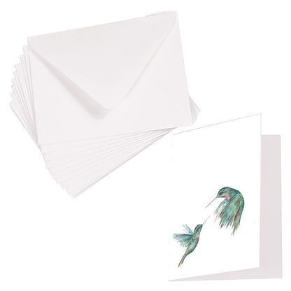 Folding cardstock greeting card featuring original watercolor piece Hummingbird Duel laying next to a stack of euro flap envelopes.