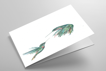 Folding greeting card featuring original watercolor piece Hummingbird Duel laying down showing cardstock thickness and blank inside.