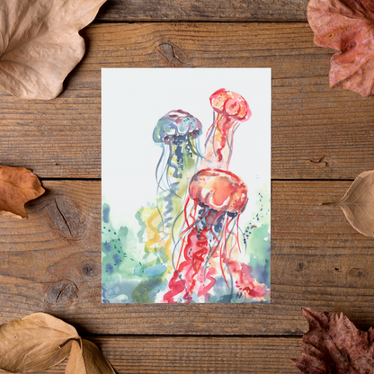 Flat cardstock note card featuring original watercolor piece Jellyfish Bloom styled on rustic wooden boards with dried autumn leaves.