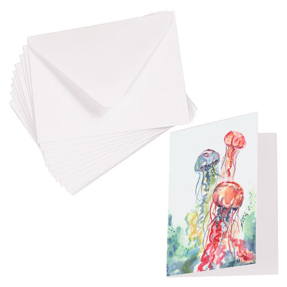 Folding cardstock greeting card featuring original watercolor piece Jellyfish Bloom laying next to a stack of euro flap envelopes.