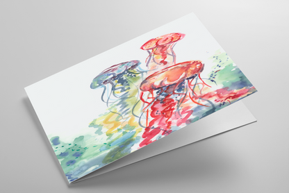Folding greeting card featuring original watercolor piece Jellyfish Bloom laying down showing cardstock thickness and blank inside.
