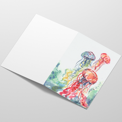 Folding cardstock greeting card featuring original watercolor piece Jellyfish Bloom laying open in a table with the outside facing up.