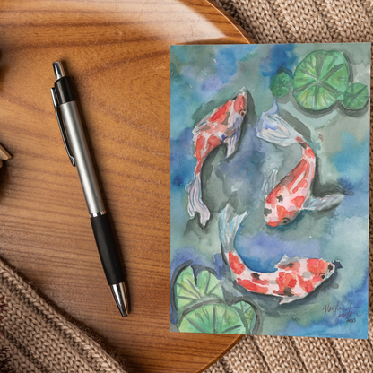 Flat cardstock note card featuring original watercolor piece Koi Pond displayed on a wooden surface beside a black and silver pen.