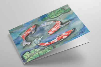 Folding greeting card featuring original watercolor piece Koi Pond laying down showing cardstock thickness and blank inside.
