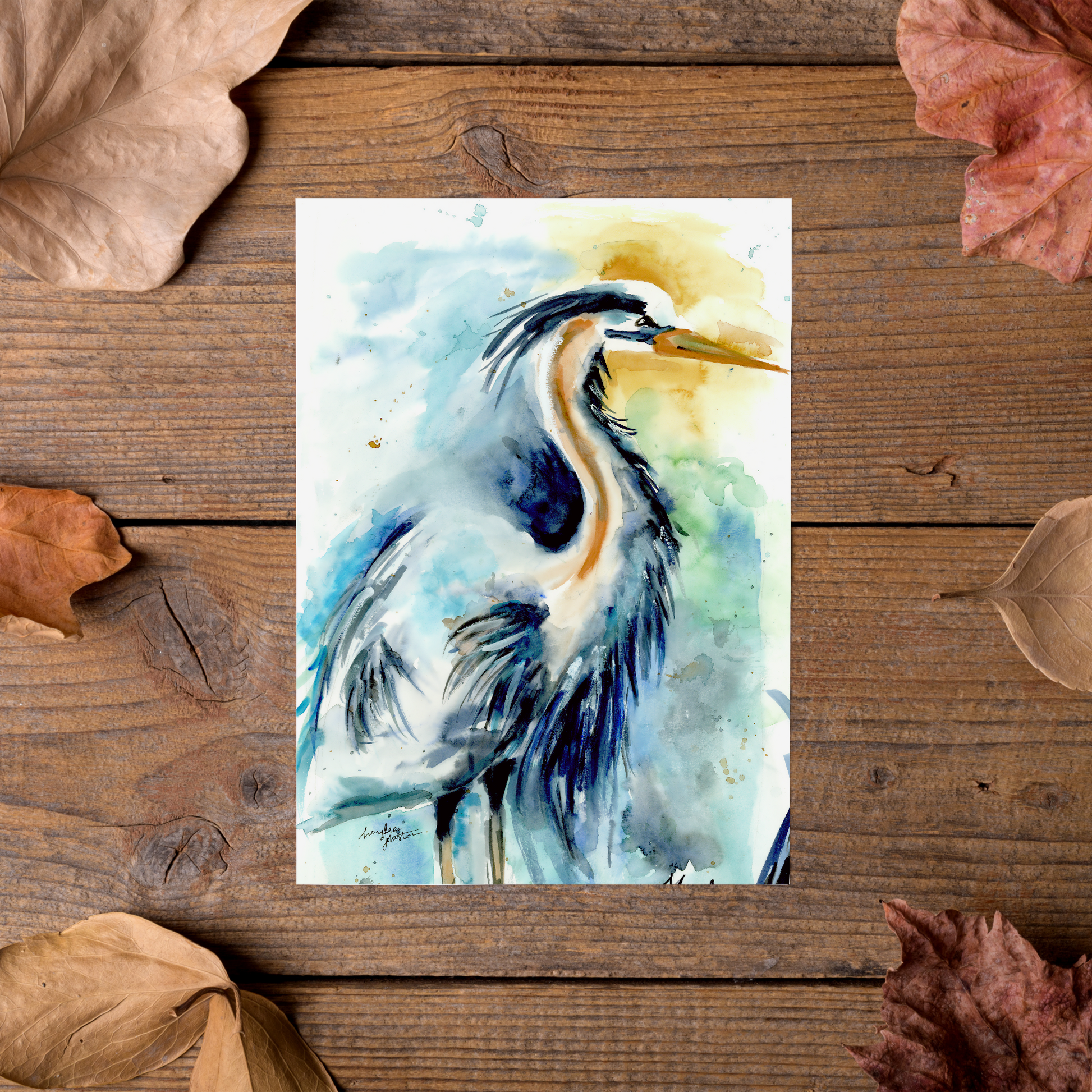 Flat cardstock note card featuring original watercolor piece Male Heron styled on rustic wooden boards with dried autumn leaves.