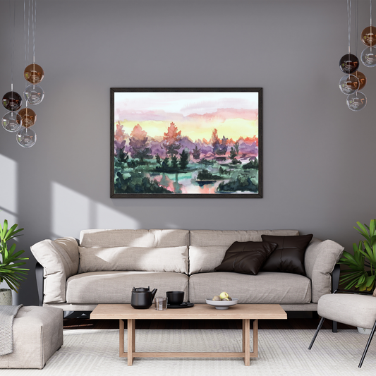 A watercolor painting of a vibrant sunrise over a lake. The sky turns from pink, to yellow, to deep purple in the trees. The water has small clumps of land with a handful of trees reflecting on the water. The art is in a black frame above a beige couch in a modern neutral living room. There is a neutral wood coffee table and a pair of plants.