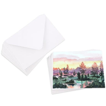 A stack of flat cardstock note cards featuring original watercolor piece Misty Sunrise next to a stack of the matching euro flap envelopes.
