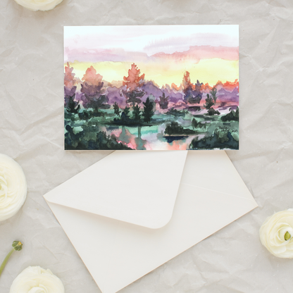 Flat cardstock note card featuring original watercolor piece Misty Sunrise and matching euro flap envelope. Styled on linen and surrounded by white flowers.