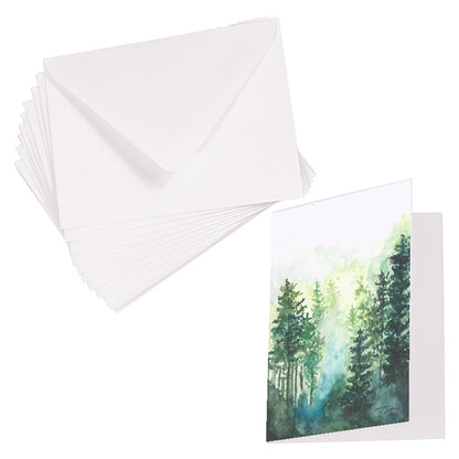 Folding cardstock greeting card featuring original watercolor piece Morning Forest laying next to a stack of euro flap envelopes.