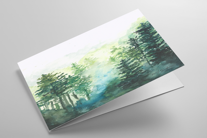 Folding greeting card featuring original watercolor piece Morning Forest laying down showing cardstock thickness and blank inside.