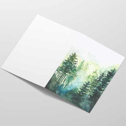Folding cardstock greeting card featuring original watercolor piece Morning Forest laying open in a table with the outside facing up.