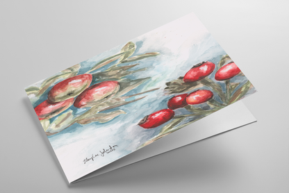 Folding greeting card featuring original watercolor piece Red Apples and Rosehips laying down showing cardstock thickness and blank inside.