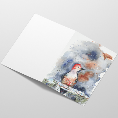 Folding cardstock greeting card featuring original watercolor piece Red Bellied Woodpecker laying open in a table with the outside facing up.