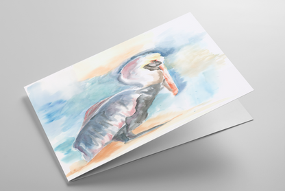 Folding greeting card featuring original watercolor piece Shy Pelican laying down showing cardstock thickness and blank inside.
